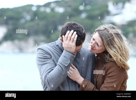 Worried Woman Comforting A Sad Man In Winter On The Beach Stock Photo