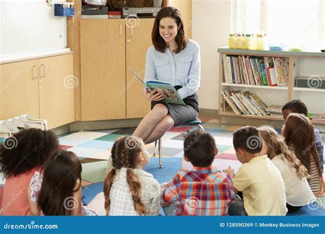 School Kids Sitting On Floor Listening To Teacher Read Stock Image