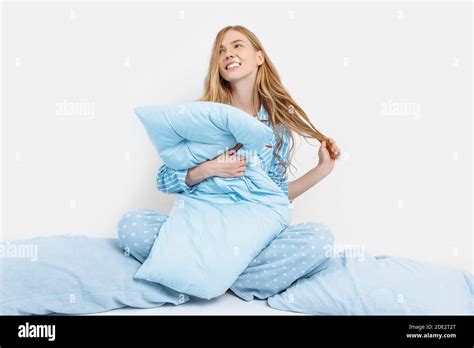 Beautiful Girl In Pajamas Sitting On The Bed With Pillows In Her Hands