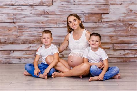 Mujer Embarazada Sonriente Con Dos Hijos Sentados En El Suelo Sobre Un
