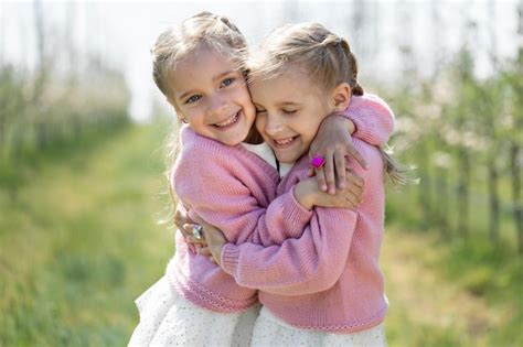 Premium Photo Happy Two Twin Sisters Are Hugging Against The