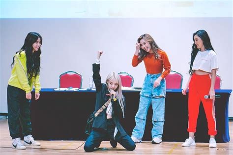 Four Girls Are Standing In Front Of A Screen And One Girl Is Holding Her Hands Up