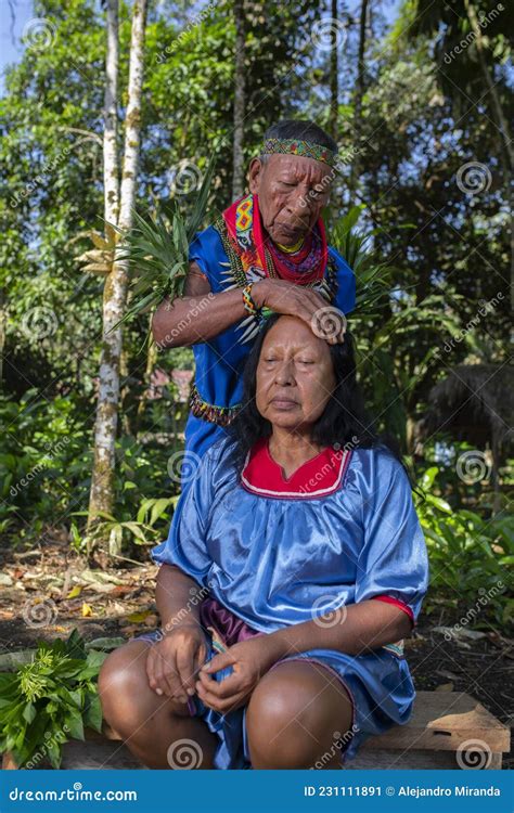 Elderly Indigenous Shaman Of Cofan Nationality Performing Healing Ritual To A Cofan Woman In The