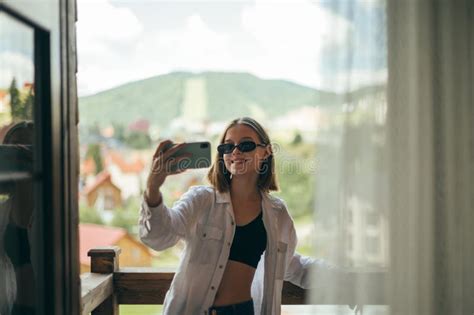 Attractive Girl Standing On The Balcony In The Apartment Taking Selfie