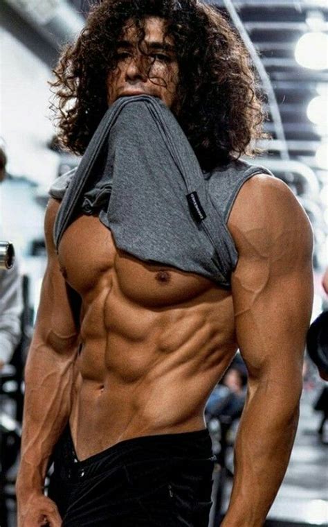 a man with long curly hair and no shirt is posing for the camera while wearing black shorts