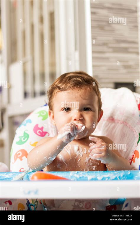 Baby Stained With Yogurt While Eating Yogurt In His High Chair To Eat