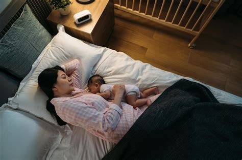 premium photo view from above asian mom wearing pajamas is sleeping while breastfeeding her
