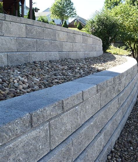 A Stone Retaining Wall Next To Trees And Bushes