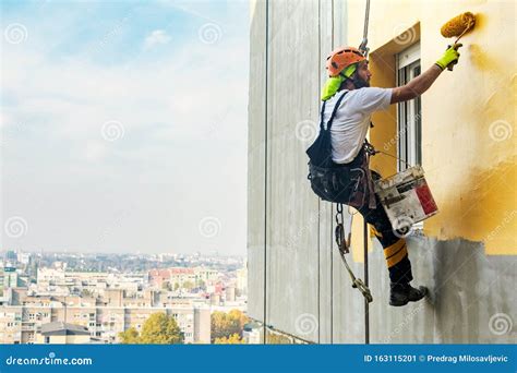 Industrial Rope Access Worker Hanging From The Building While Painting