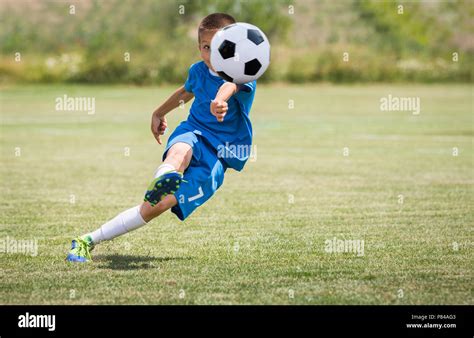 Niño Pateando Una Pelota De Fútbol En El Campo De Deportes Fotografía