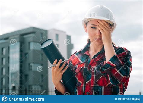 A Brooding Female Builder With Drawings Of Papers In Her Hands Stock