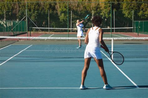 African American Female Player Playing Tennis Game With Young Caucasian