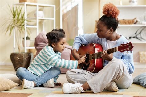 Madre Tocando La Guitarra Con Su Hija En Casa Foto Premium