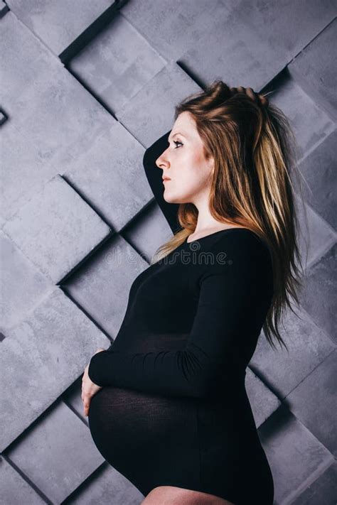 A Pregnant Woman In Lingerie With A Big Belly In The Ninth Month Of Pregnancy Is Posing Next To