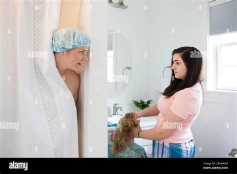 Una mamá está en la ducha mientras sus hijas se preparan en el baño Fotografía de stock Alamy