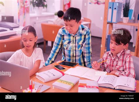 Three Smiling Children Helping Each Other With Homework Stock Photo Alamy