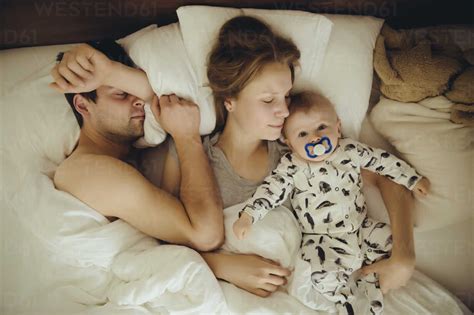 Mother Father And Baby Boy Cuddling In Bed Stockphoto