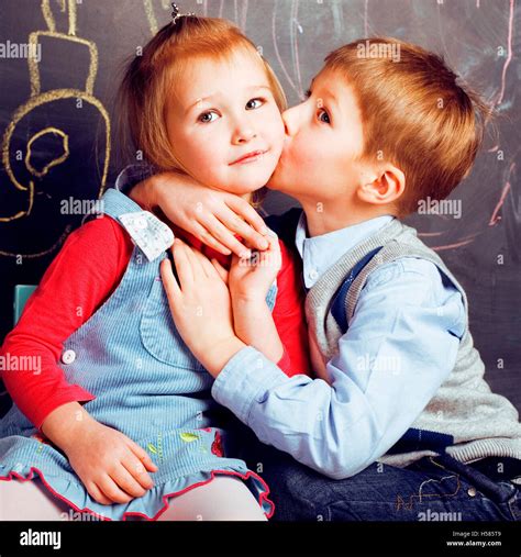 Little Cute Boy Kissing Blonde Girl In Classroom At Blackboard First