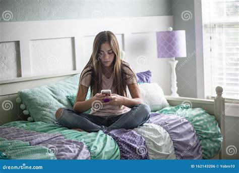Pre Adolescent Teen Girl Reading A Book Lying In Bed At Home Candid Indoor Photo With Focus On