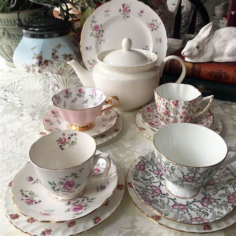 A Table Topped With Lots Of White And Pink China Cups And Saucers On