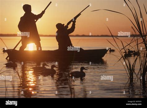 Two Men Duck Hunting From Skiff At Sunset On Lake Stock Photo Alamy