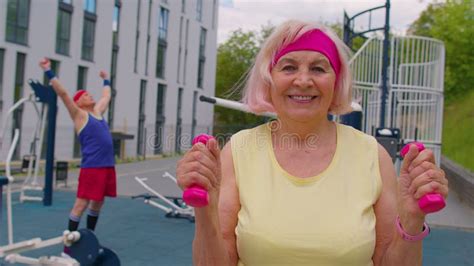 Senior Woman Grandmother Athlete Doing Routine Weightlifting Dumbbells Exercises On Playground