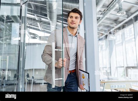 Handsome Young Businessman With Clipboard Entering The Door In Office