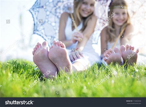 Two Girls Sitting On The Grass With Bare Feet Stock Photo 115402636