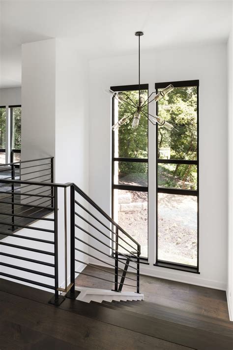 Modern Staircase With A Chandelier And Large Windows Viewing Out In The