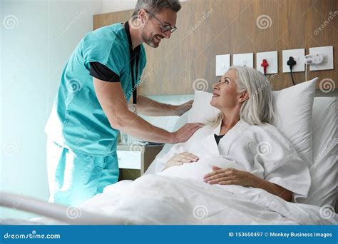 Surgeon Visiting And Shaking Hands With Mature Female Patient In Hospital Bed Royalty Free Stock