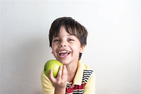 Joli Garçon Mangeant Une Pomme Verte Photo Gratuite