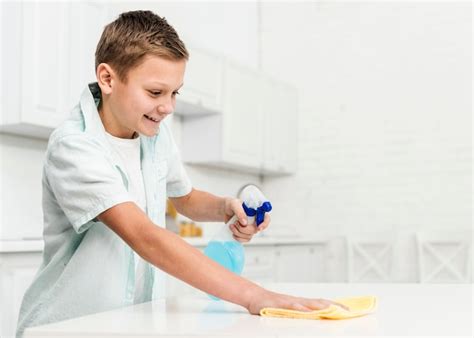 Free Photo Side View Of Happy Boy Cleaning Table With Rag