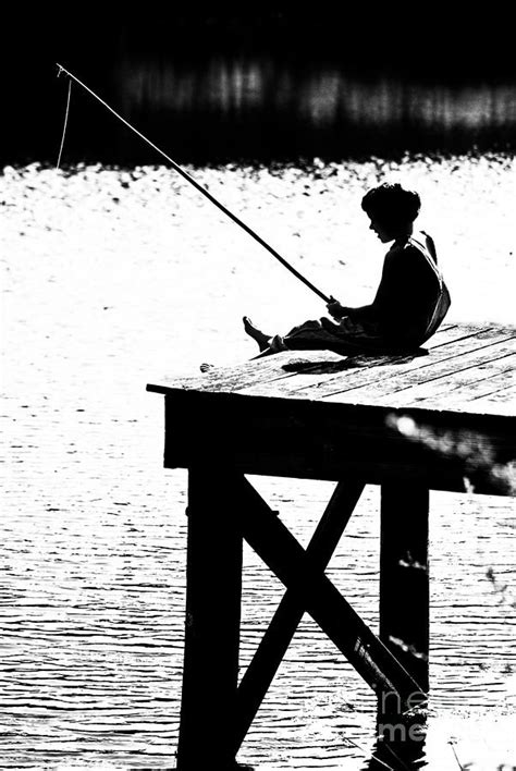 Silhouette Of A Boy Fishing From A Dock On Lake Or Pond Photograph By