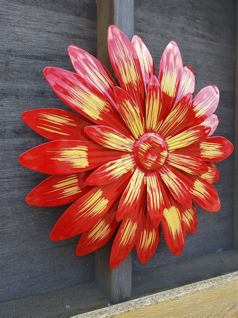 A Red And Yellow Flower Sitting On Top Of A Wooden Table Next To A Wall
