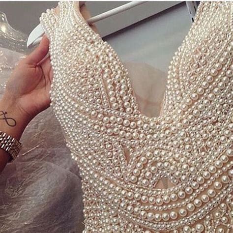 A Woman Is Showing Off Her Wedding Dress With Pearls On The Neck And Sleeves