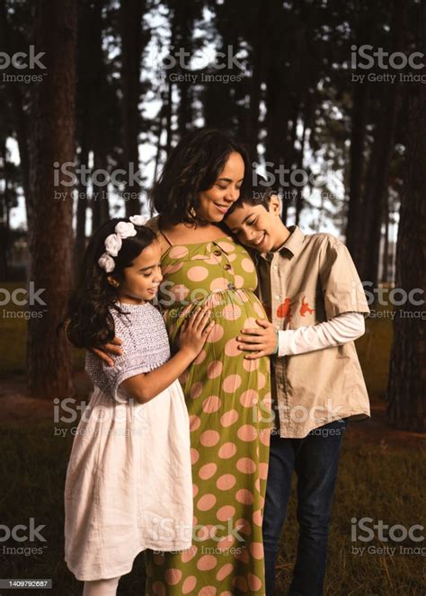 Pregnant Latin Mom Hugging Her Son And Babe In Pine Forest Stock