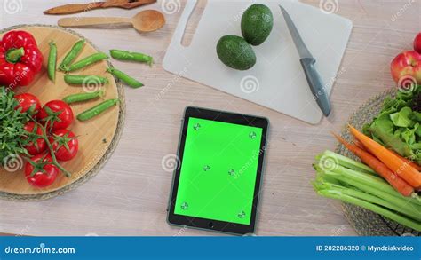 Tablet With Green Screen In The Kitchen On Table With Fresh Vegetables