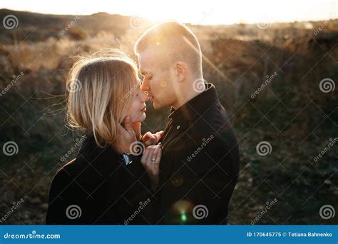 Side View Portrait Of Two Young Lovers Kissing On The Sunset Stock
