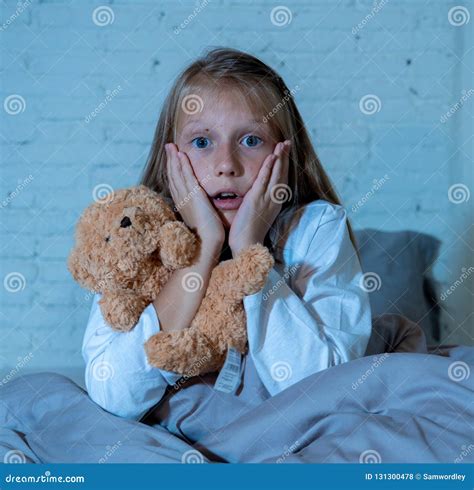 Scared Little Girl Covering Face With Hands In Fear In Darkness At