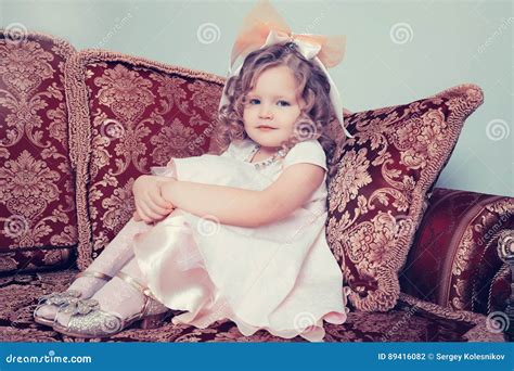 menina que senta se no sofá que abraça seus joelhos com suas mãos foto de stock imagem de