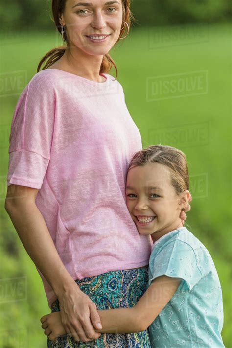 Portrait Of Smiling Girl Hugging Mother On Field Stock Photo Dissolve