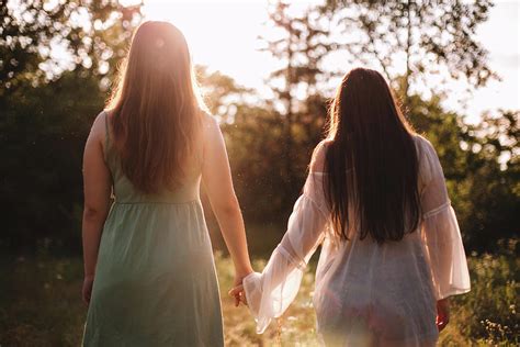 back view of lesbian couple holding hands while standing in forest photograph by cavan images