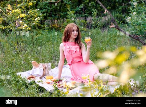 Pretty Young Redhead Girl In Pink Dress Having Summer Picnic In Park