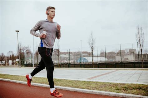 Young Man Running On Tartan Track — Motivation Vitality Stock Photo