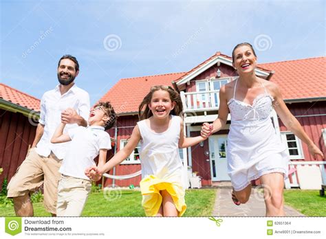 Familia Feliz Que Corre En Prado Delante De La Casa Foto De Archivo