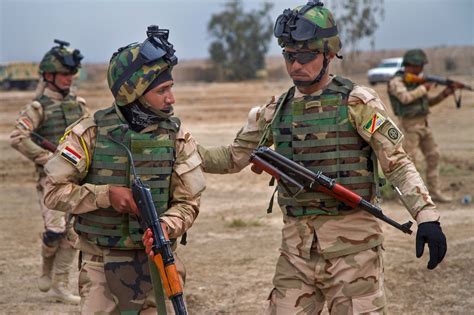 An Iraqi Army Sergeant Right Guides One Of His Soldiers Into A Proper