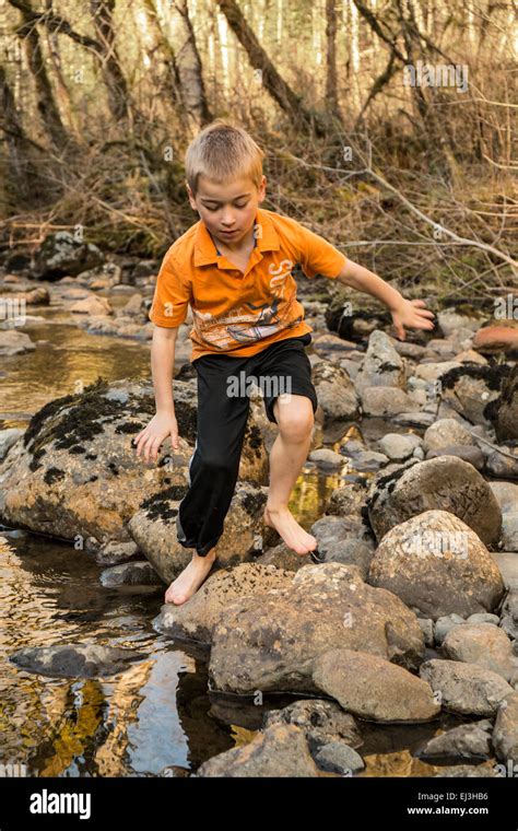 Seven Year Old Barefoot Boy Climbing On Rocks In The Snoqualmie River