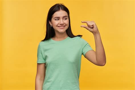 Lächelnde Süße Brünette Junge Frau In Mint T Shirt Die Mit Den Fingern über Gelber Wand