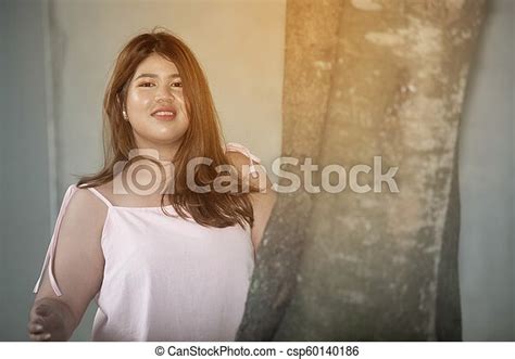 Portrait Of Asian Pretty Smiley Face Fat Woman Pose Standing Behind The Tree In Front Of The