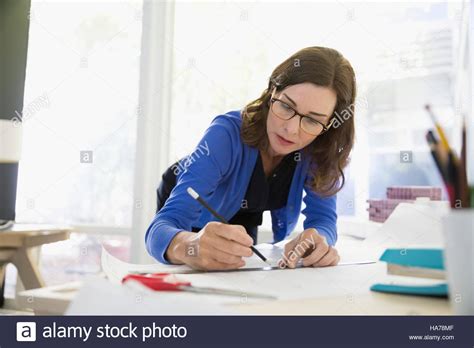 Female Architect Drafting Blueprint With Ruler And Pencil Stock Photo